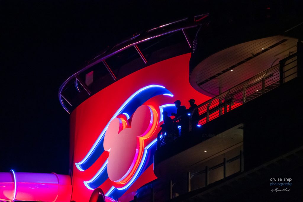 Mitarbeiter an Bord der Disney Destiny vor dem markanten roten Schornstein mit dem Mickey Mouse Symbol